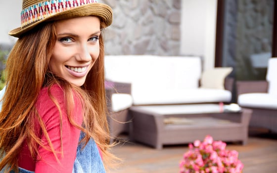 donna con cappello e maglia rossi di fronte a mobili da giardino