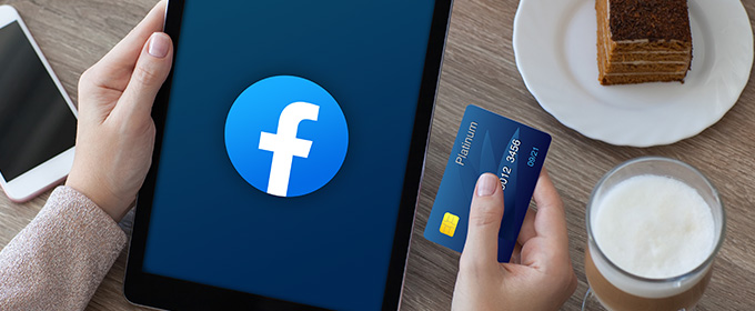 kobieta przeglądająca facebooka i trzymająca kartę płatniczą