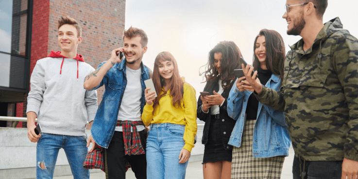 Grupa młodych ludzi z pokolenia Z przy swoich telefonach komórkowych