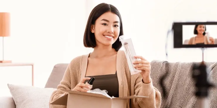 Uśmiechnięta kobieta prezentuje kosmetyki kupione online do kamery