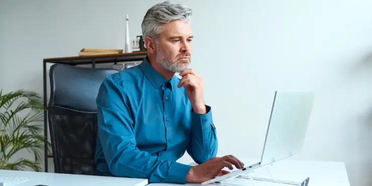 Zmartwiony mężczyzna patrzy w ekran laptopa